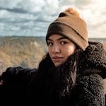 A woman in a beanie and coat enjoying a forest view during winter in Druskininkai, Lithuania.